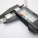 Digital caliper measuring the Gucci 102 G-frame watch case, showing a precise reading of 14.7mm.