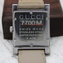 Close-up of the polished stainless steel case back with "GUCCI 7700M", "SWISS MADE", "STAINLESS STEEL", "WATER RESISTANT 3 ATM", and serial number engraving.