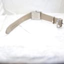 View from behind the watch showing the full length of the beige leather strap and its stainless steel buckle.