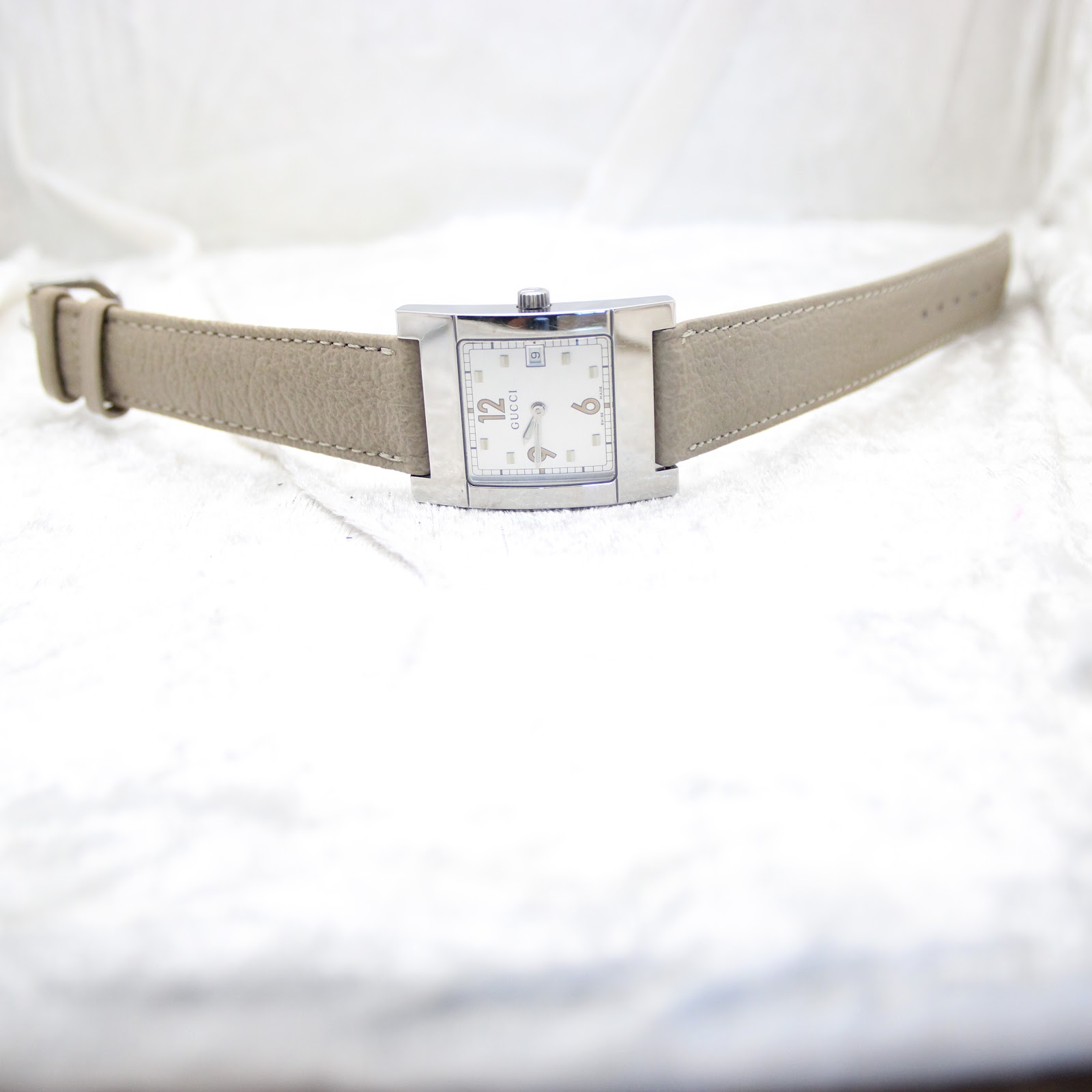 Angled front view of the Gucci 7700M from a distance, showing the watch and strap on a white background.