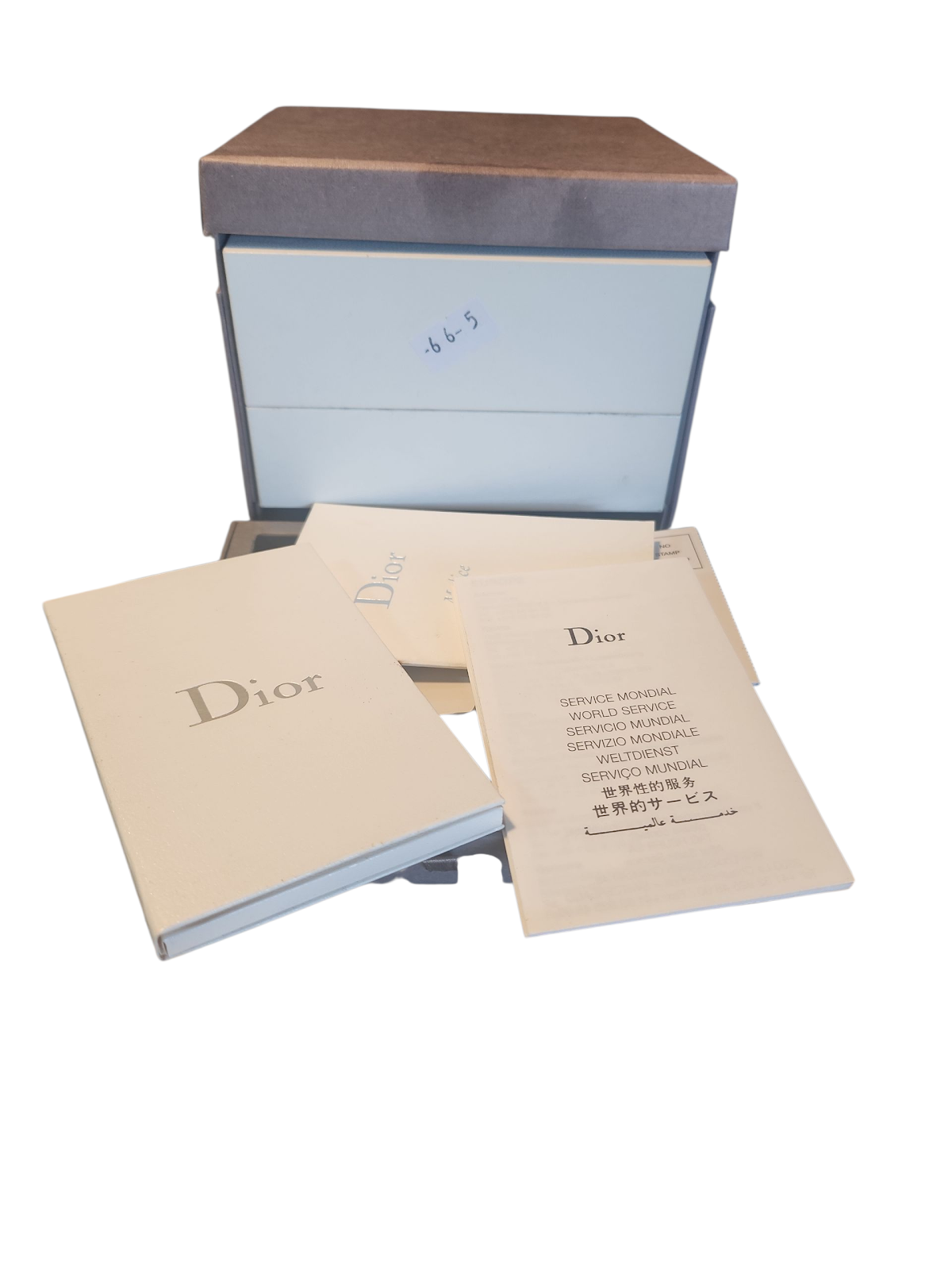 A stack of Dior branded papers and a brown box, unrelated to the Gucci watch.