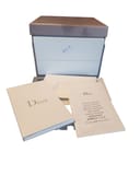 A stack of Dior branded papers and a brown box, unrelated to the Gucci watch.