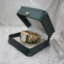 The Gucci 8500L watch placed inside a generic green watch box, on a white textured surface.