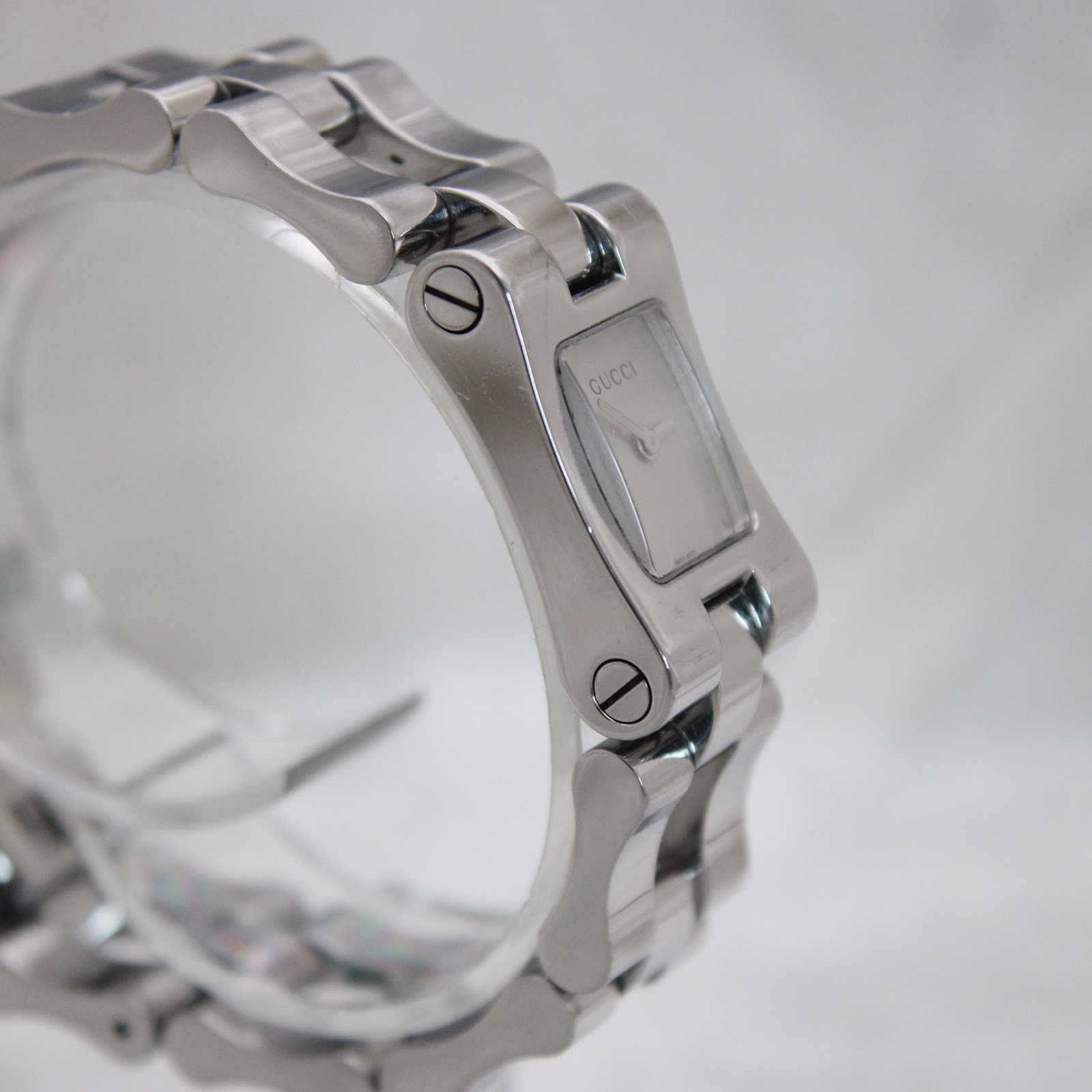 Another angled side view of the Gucci 2305L watch, focusing on the connection points of the bracelet links and the curved profile of the case.