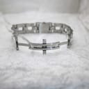 Interior view of the stainless steel bracelet, showing the hidden deployant clasp mechanism open on a white textured surface.