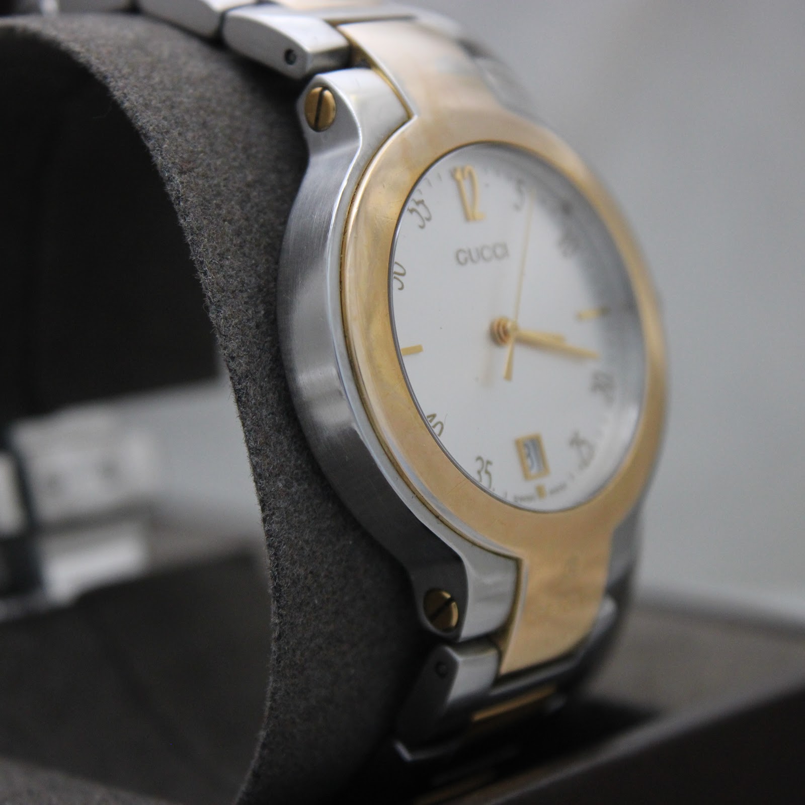 Reverse angled side view of the Gucci 8900M, showing the two-tone bracelet connection points and the gold-tone bezel.