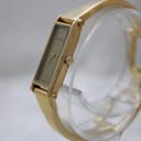 Angled view of the Gucci 1500L watch, highlighting the gold-tone case, crown, and the seamless design of the bangle.