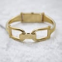 Slightly different angled view of the open Gucci-signed bangle clasp, showing its construction and the gold-tone finish.