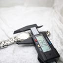 Digital caliper measuring the case diameter of the Gucci 8900L watch at 26.0mm, confirming its size.