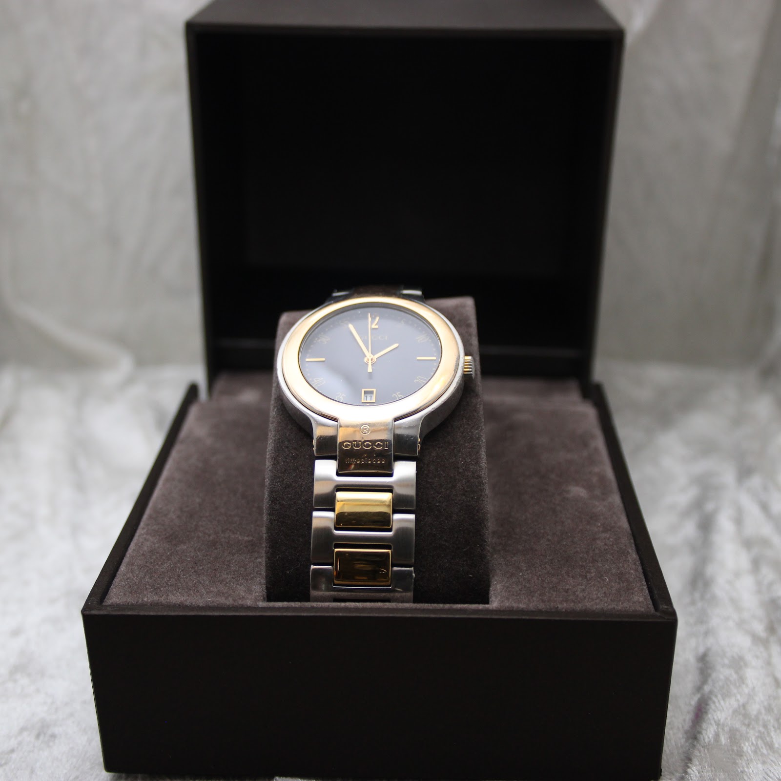 Front view of the Gucci 8900M watch presented within its original dark brown Gucci display box.
