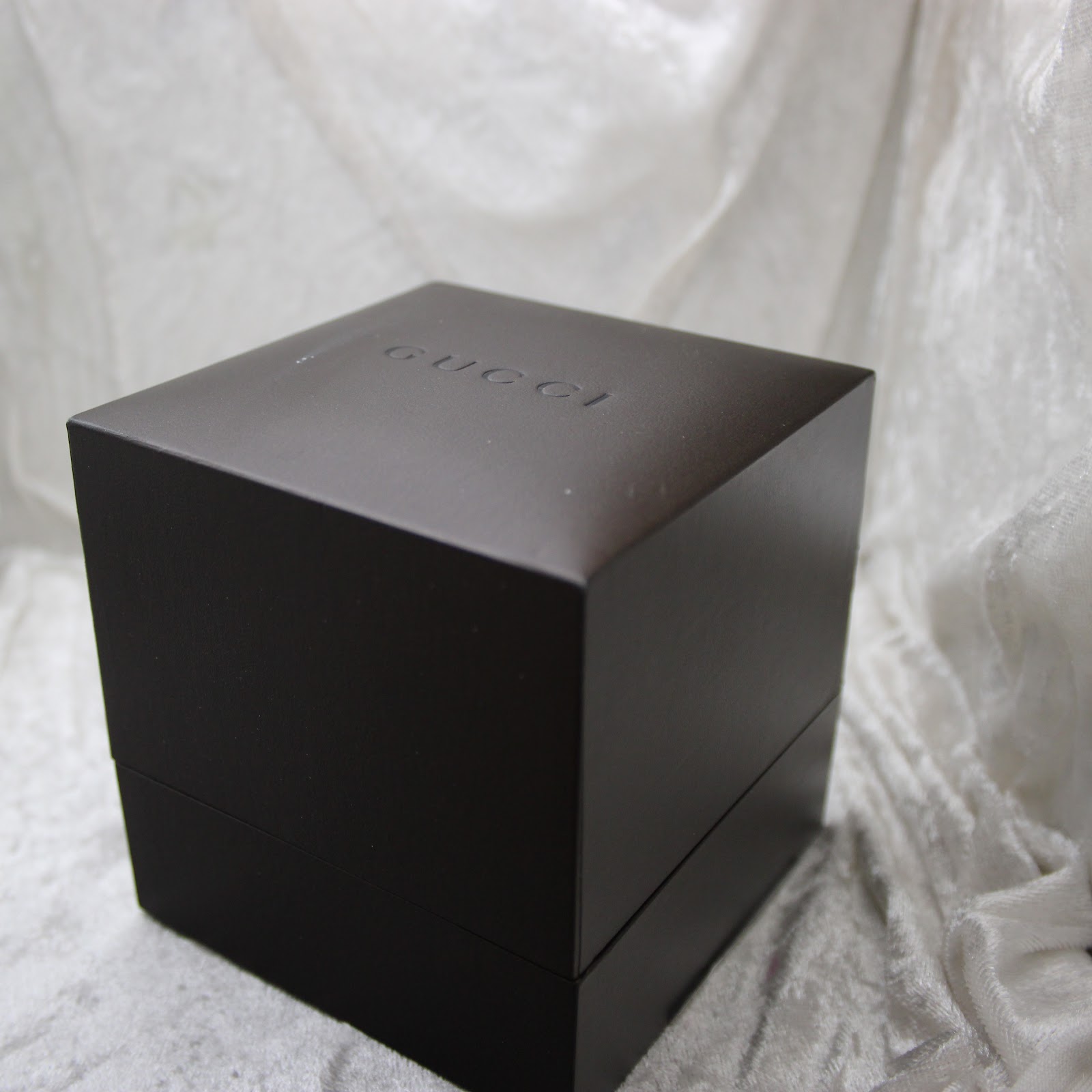 Overhead view of the closed original dark brown Gucci watch box, with the Gucci logo embossed on the lid.