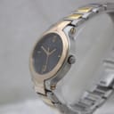 Angled side view of the Gucci 8900M watch, highlighting the crown with Gucci logo and the profile of the gold-tone bezel.