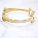 Side profile view of the gold-tone bangle bracelet, showing the curve and some wear on the gold plating.