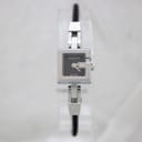 Front view of the Gucci 102 watch on a clear stand, showing its black square dial and stainless steel case with a G-shaped crown.