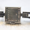 Close-up of the watch case back, revealing engravings: 'WATER RESISTANT 3 ATM', 'GUCCI', '102', 'SWISS MADE', 'STAINLESS STEEL', and model '2403'.