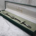 The Gucci 102 watch resting inside its opened original green Gucci box, which has a cream fabric interior.