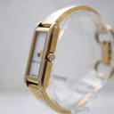 Angled view of the Gucci 109 watch, showing the gold-tone crown and the two-tone bangle bracelet.