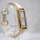 Side view of the Gucci 109 watch on a clear display stand, highlighting the rectangular case and white dial.