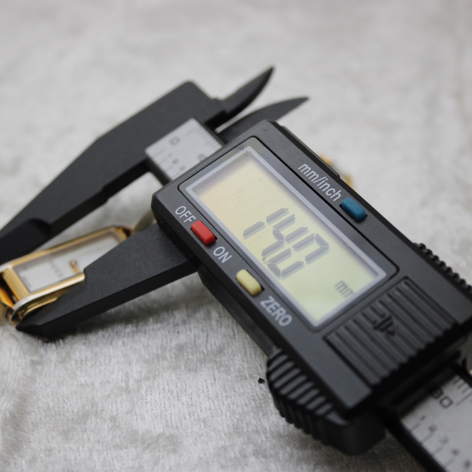 Digital caliper measuring the watch case, displaying a precise reading of 14.0 mm for the case diameter.