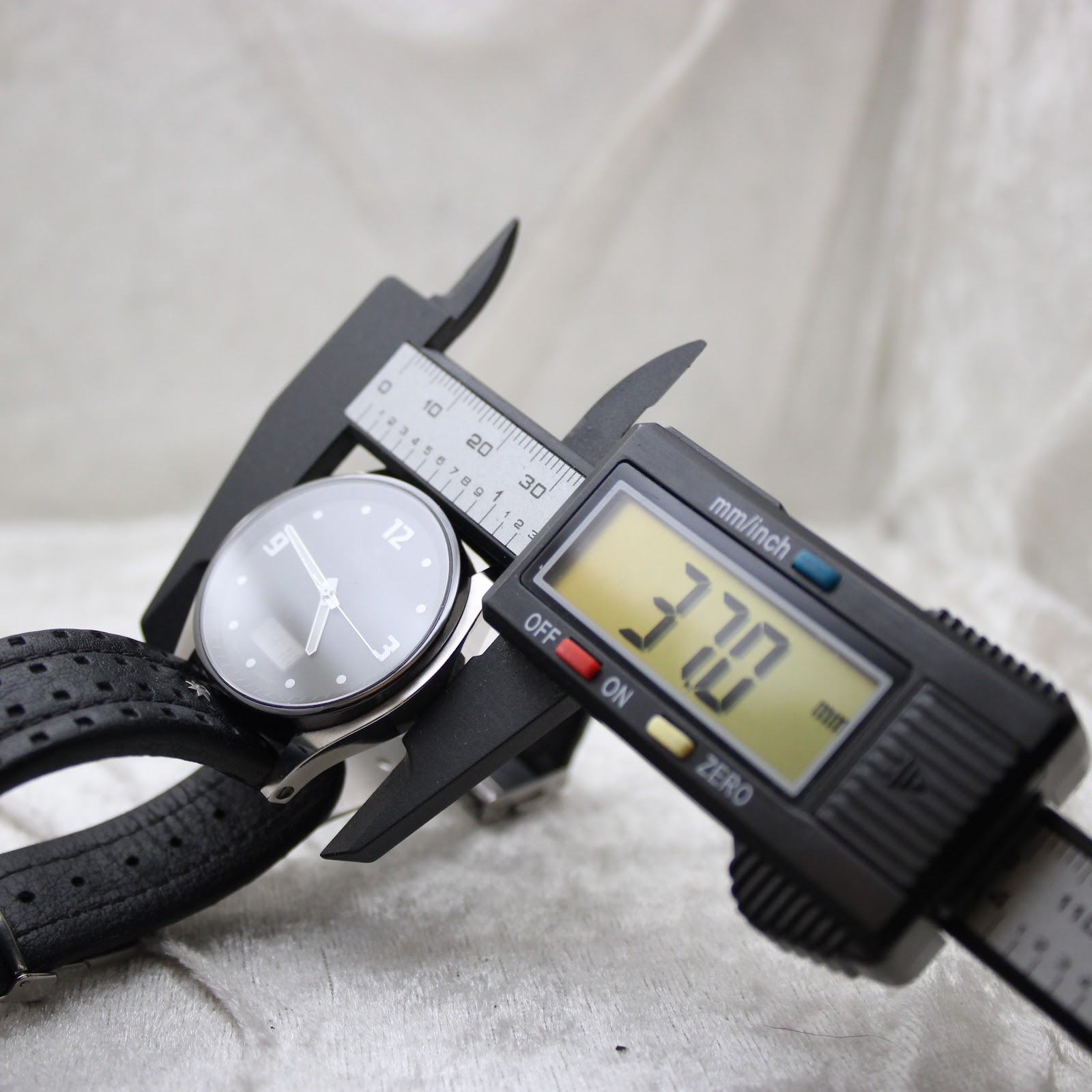Digital caliper accurately measuring the watch's case diameter at 37.0mm.