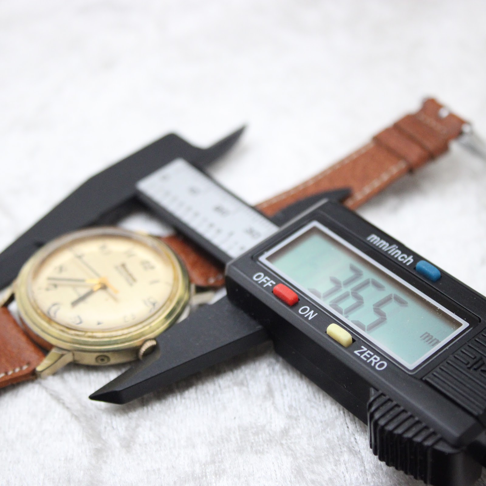 Digital caliper measuring the case diameter as 36.5 mm, with the watch and strap in the background.