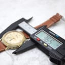 Digital caliper measuring the case diameter as 36.5 mm, with the watch and strap in the background.