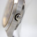 Close-up of the watch crown, detailed with an engraved 'R' logo.