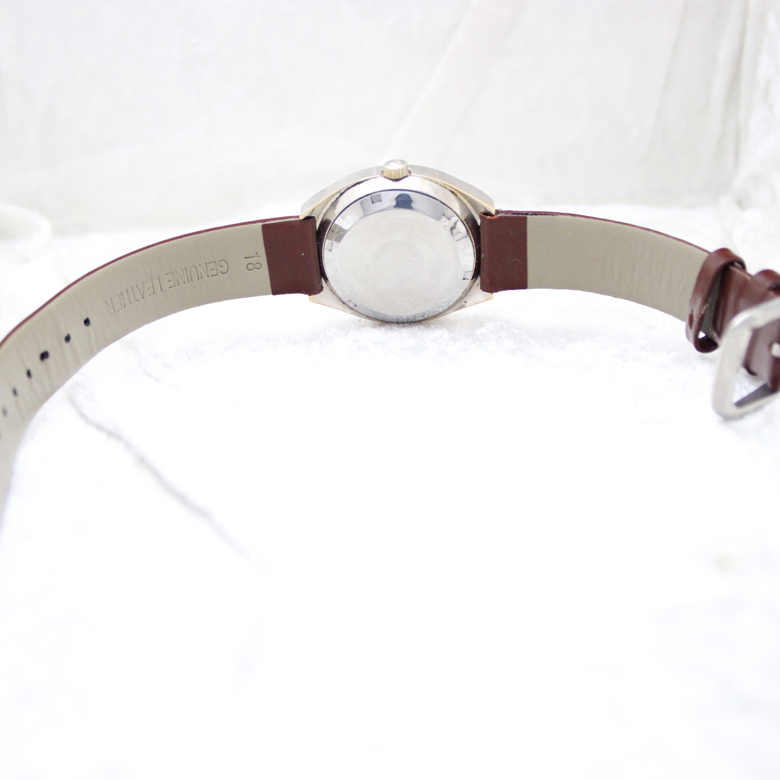Rear view of the watch showing the brown genuine leather strap with an 18mm lug width marking, and the stainless steel case back.
