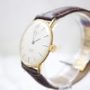 Angled side view of the gold-plated Rotary watch case and crown on a brown leather strap.