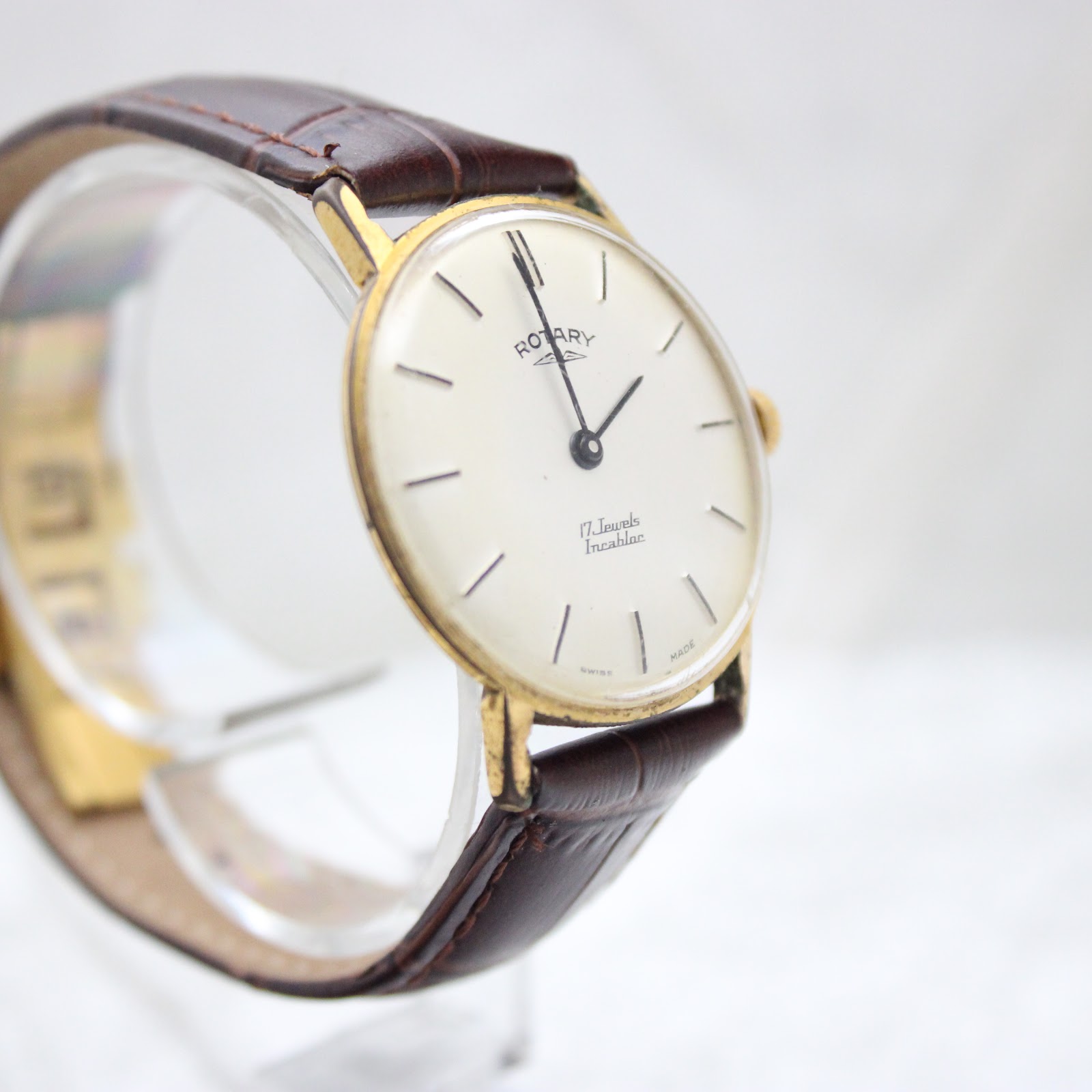 Another angled view showing the Rotary watch dial, gold-tone case, and brown leather strap.