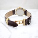 Close-up of the gold-tone butterfly deployant clasp on the brown leather strap.