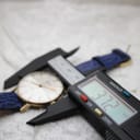Digital caliper measuring the watch case diameter at 37.72mm, resting on a white surface.