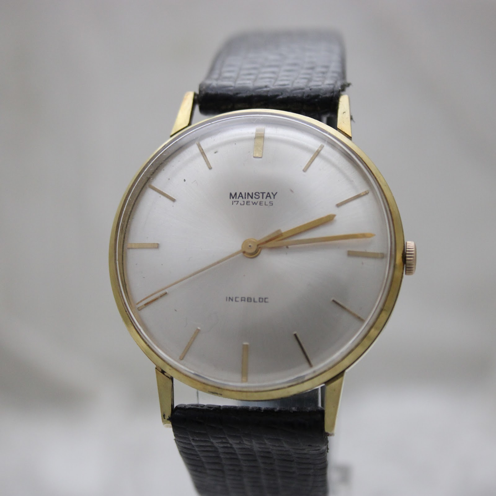 Second front view of the Mainstay watch with a clear view of the silver sunburst dial and gold baton indices.