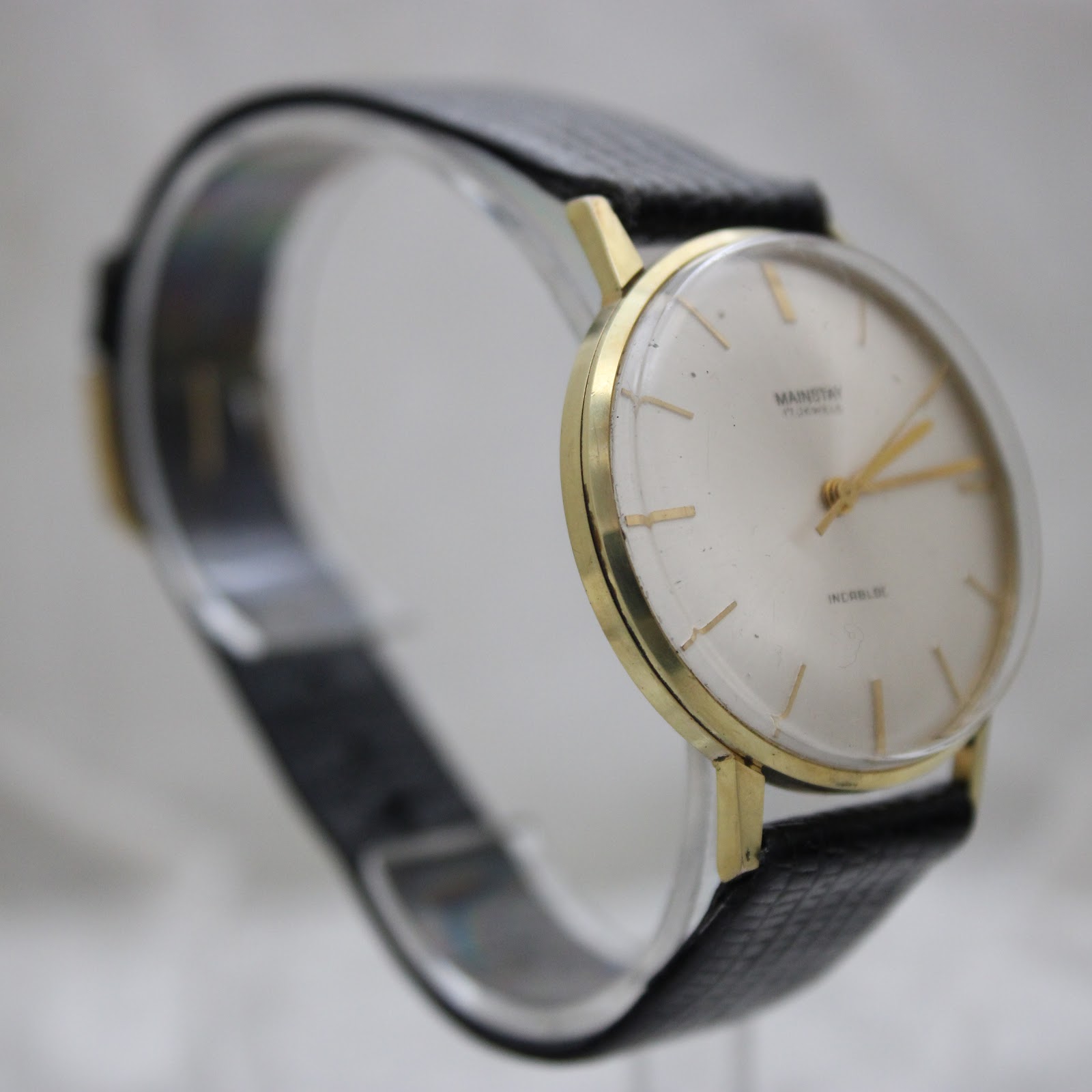Second three-quarter view of the Mainstay watch on a clear stand, showing the classic dress watch design.