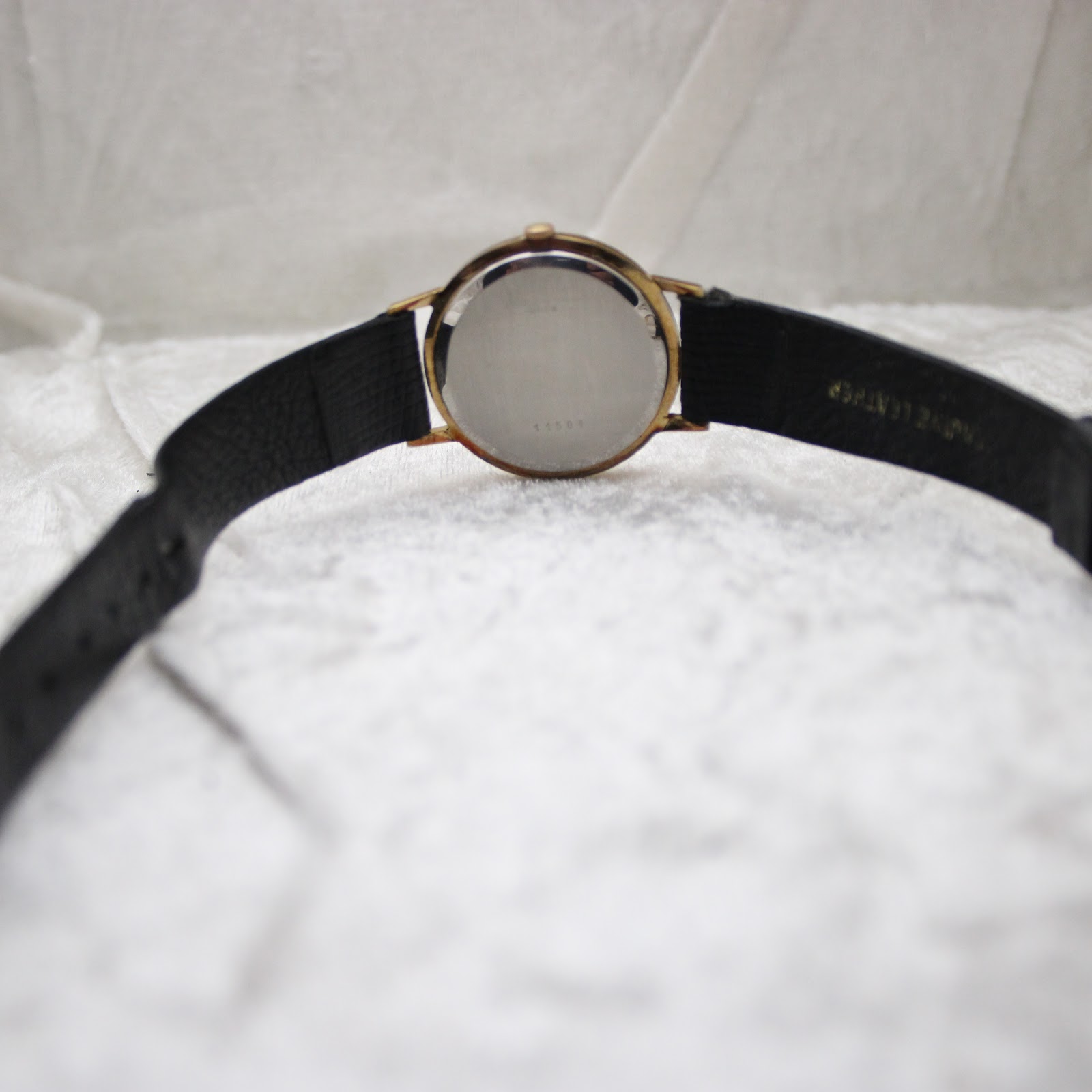 Rear view of the Mainstay watch showing the stainless steel case back and the full length of the black leather strap.