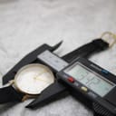 Close-up of a digital caliper measuring the watch case diameter at 34.2mm, excluding the crown.