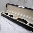 The Mainstay watch displayed in an open vintage black watch box with cream interior.