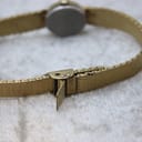 Close-up of the simple fold-over clasp mechanism on the integrated gold-tone bracelet.