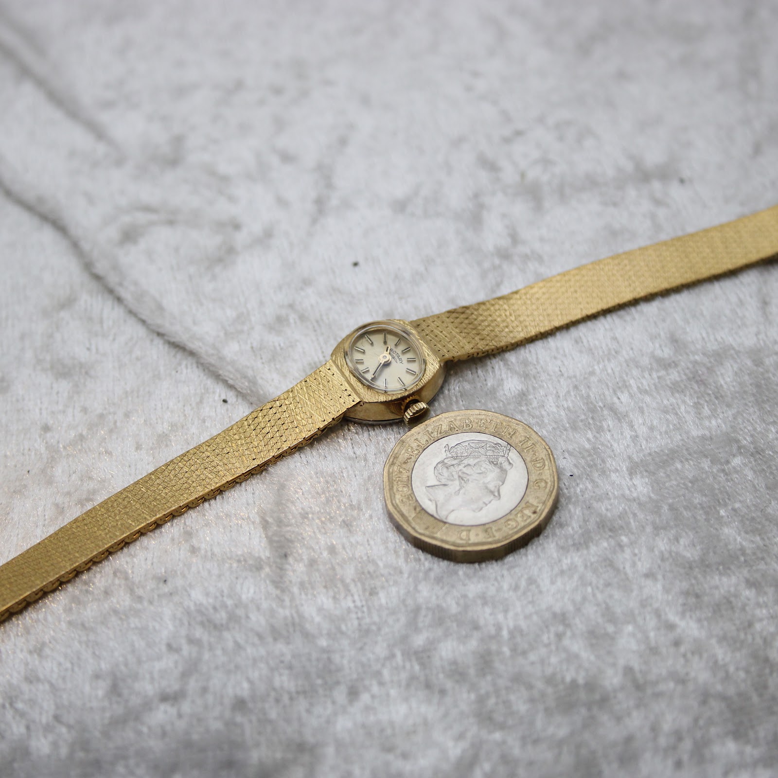 Full length view of the watch and bracelet alongside a UK £1 coin for size comparison.