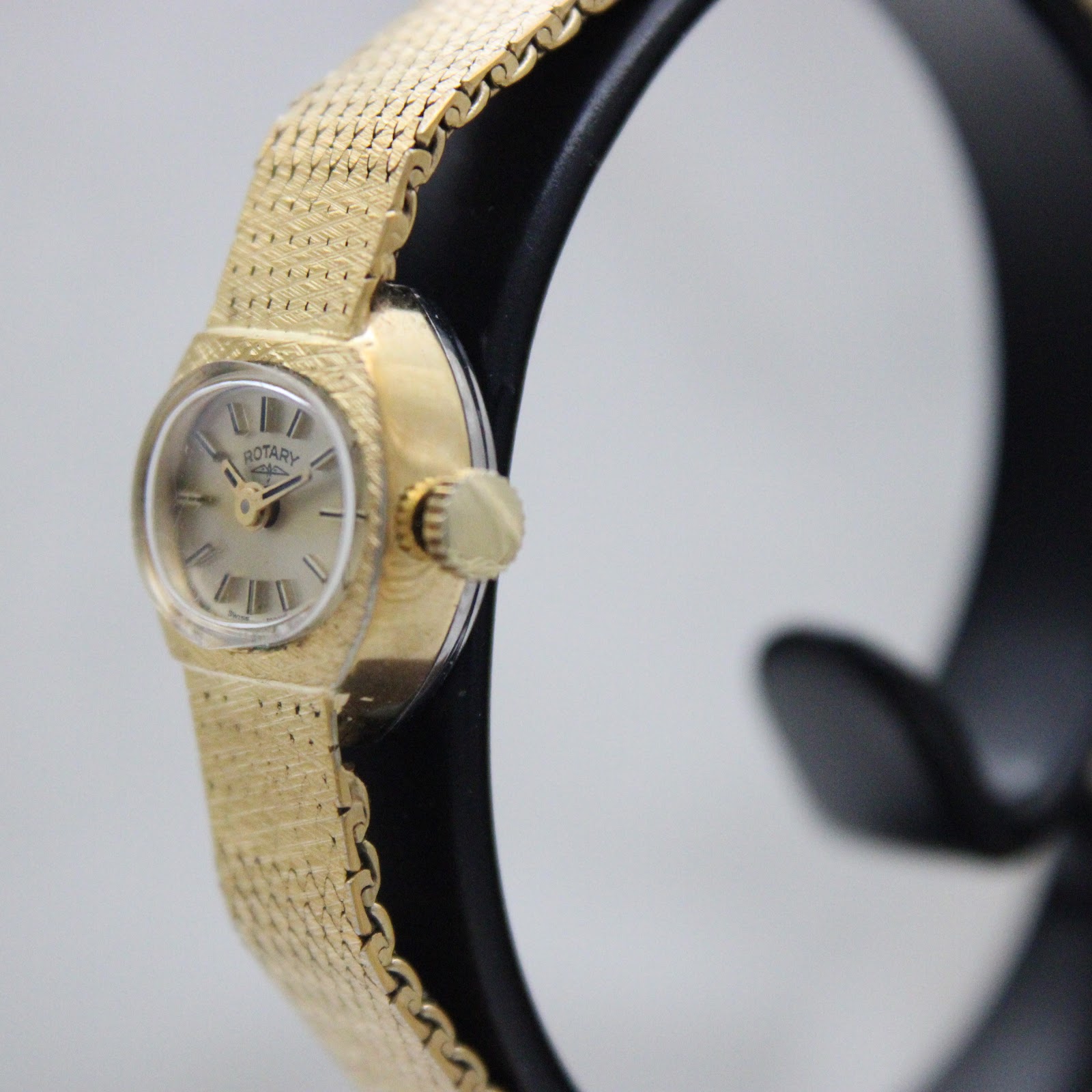 Side-angled view of the Rotary watch, showing the fluted crown and integrated bracelet.