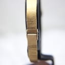Close-up side view of the integrated gold-tone bracelet's clasp mechanism.