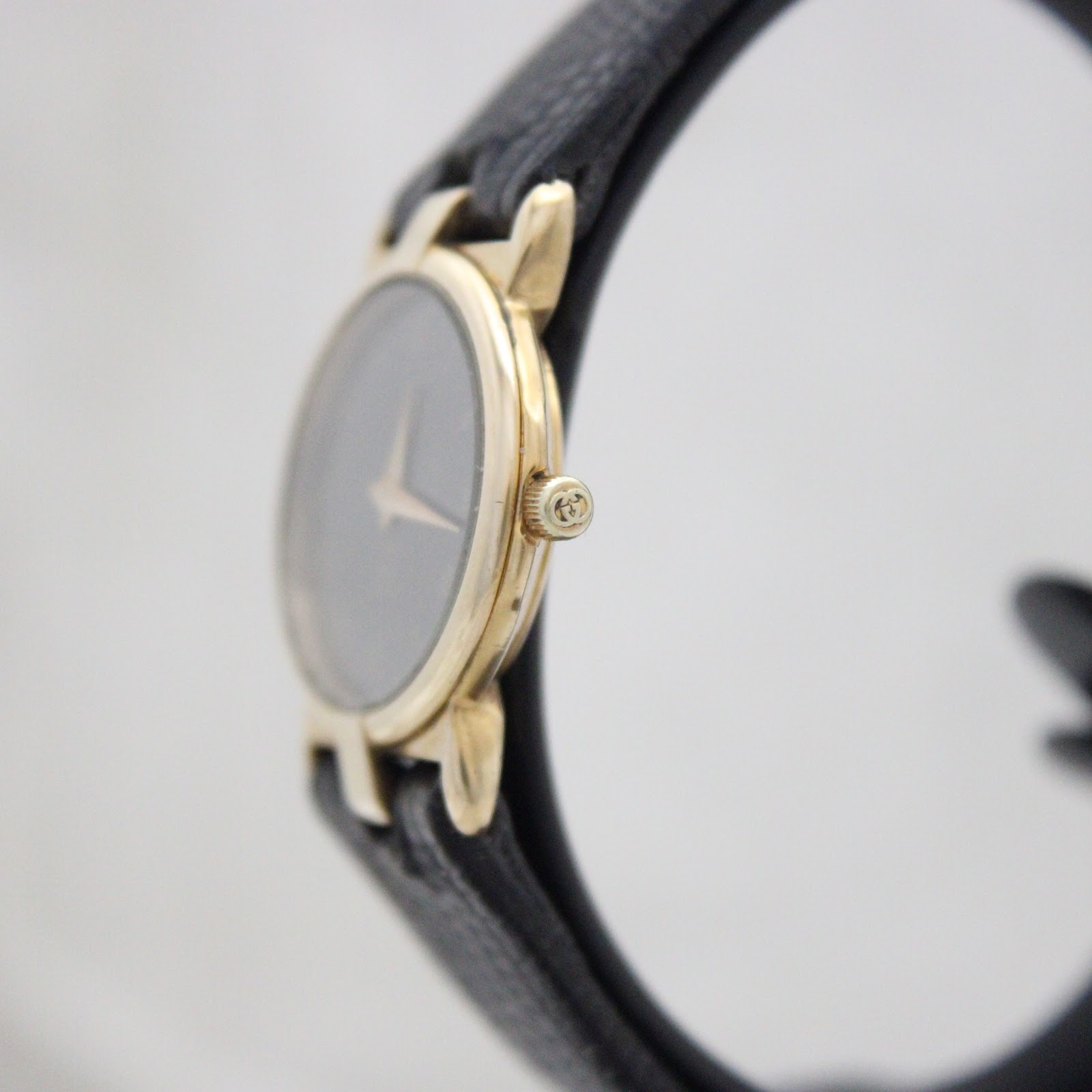 Side profile view of the gold-plated Gucci watch showing the signed crown.