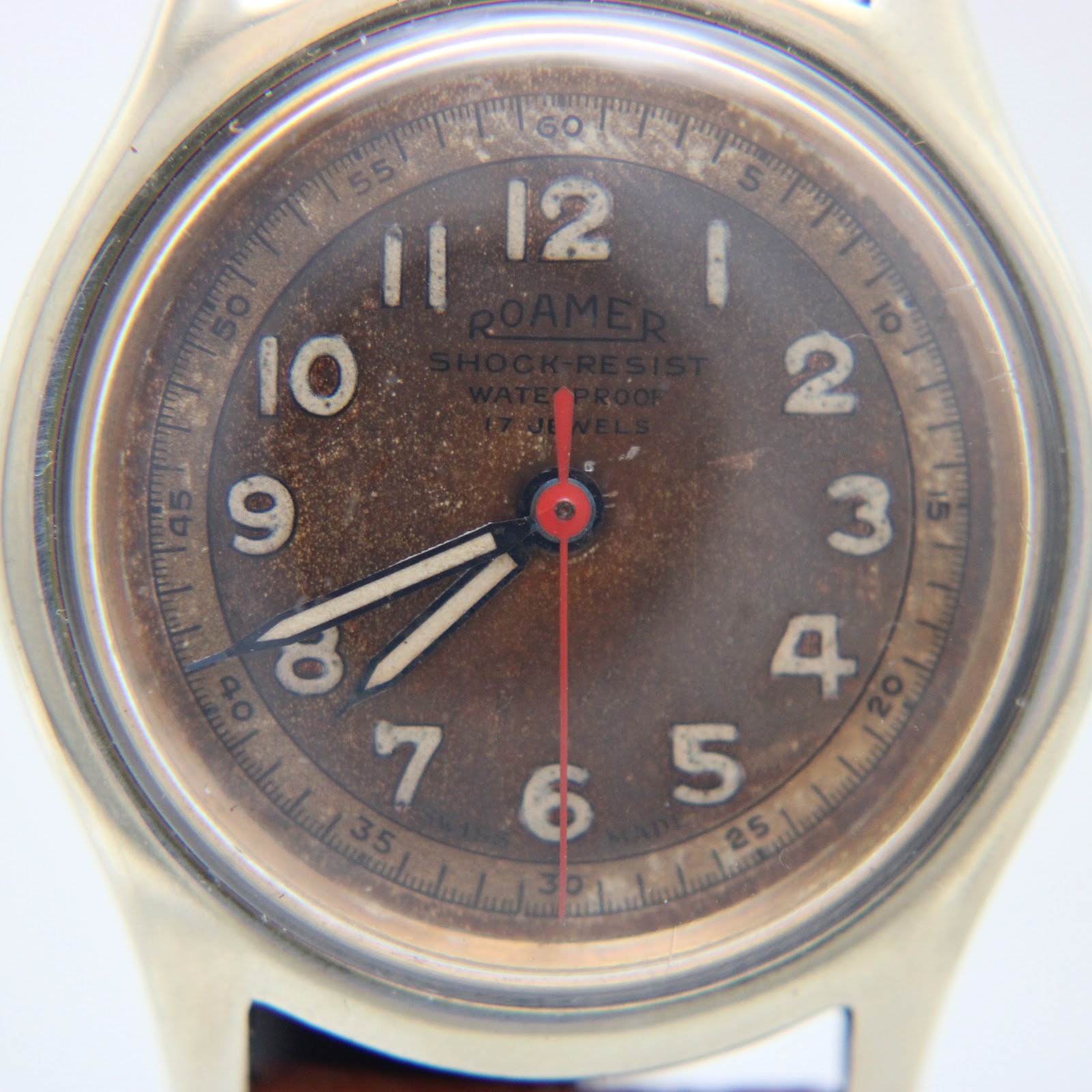 Close-up of the Roamer dial, revealing the heavy brown patina, original numerals, and red seconds hand.