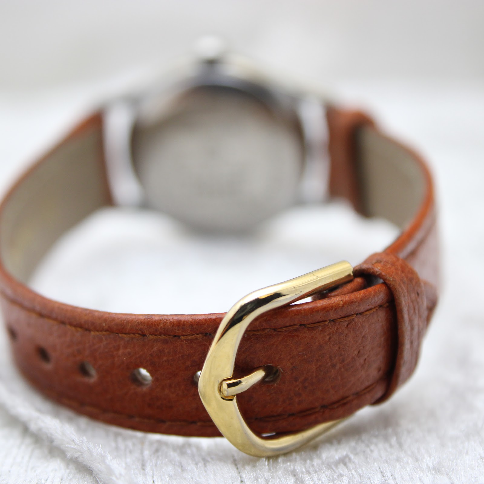Close-up of the brown leather strap with a simple gold-tone buckle.