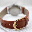 Close-up of the brown leather strap with a simple gold-tone buckle.