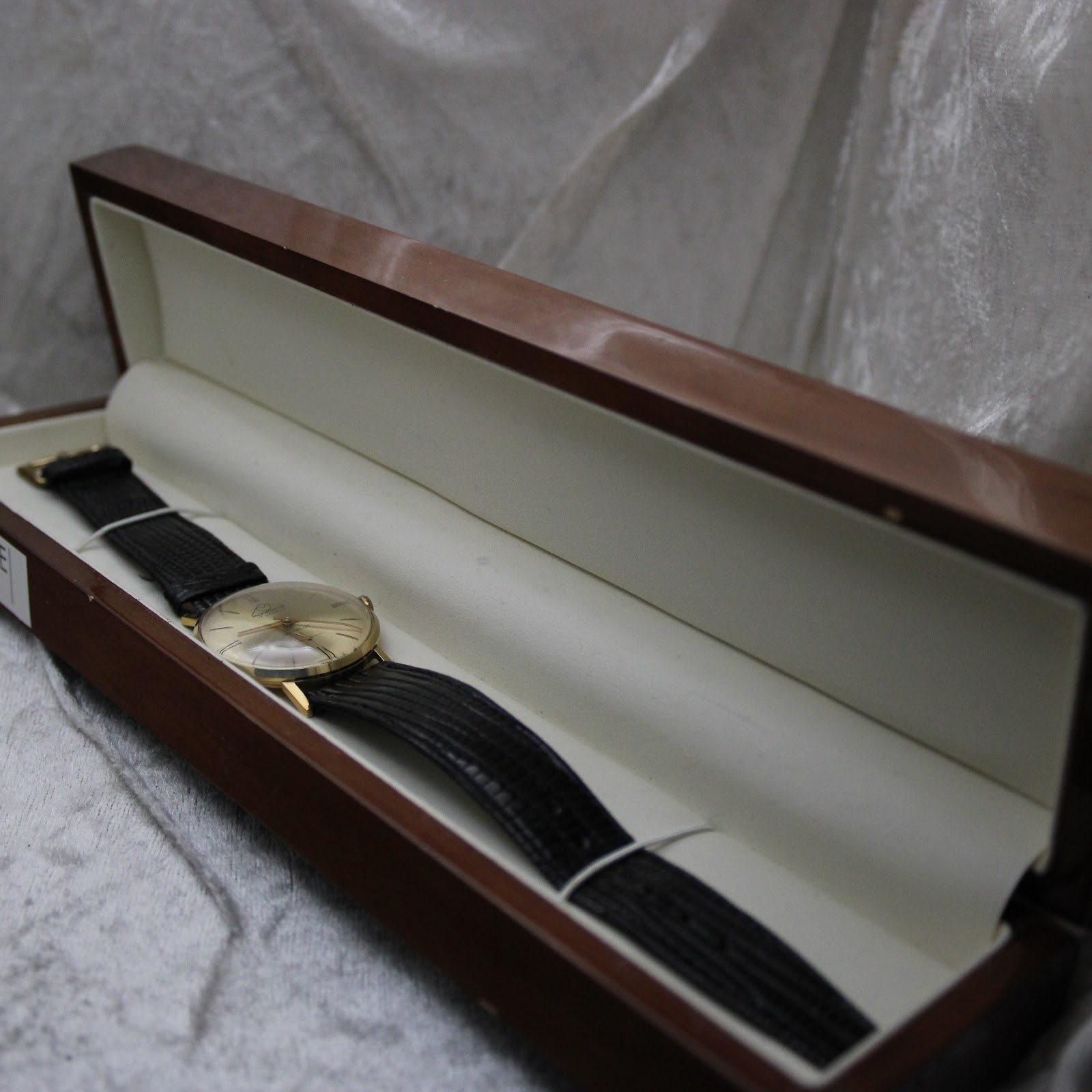 The Mondaine watch laid inside a wooden presentation box with a cream interior.