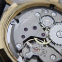 Close-up of the open case back revealing the gold-toned Swiss manual wind movement, signed 'MONDAINE WATCH LTD UNADJUSTED SEVENTEEN JEWELS'.
