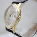 Side view of the Aristocrat watch showing the unsigned crown and gold-tone case on a display stand.