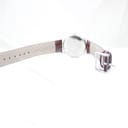 View of the watch from the underside, showing the reverse of the burgundy brown leather strap and pin buckle.