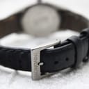 Close-up of the stainless steel buckle on the black leather strap, signed "MONDAINE"